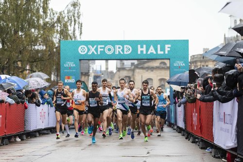 Image shows people running in the Oxford half marathon under an arch.