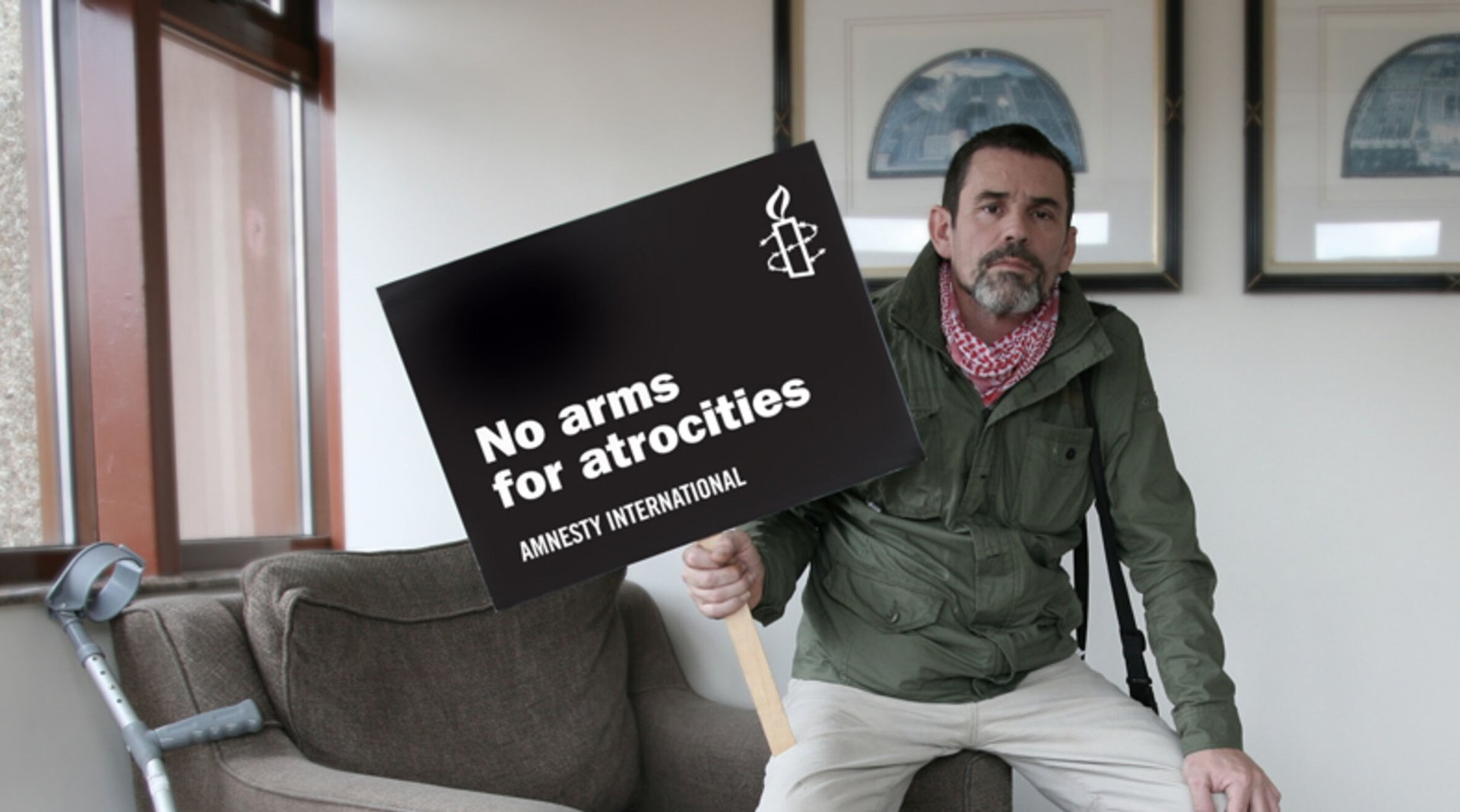 Paul Conroy holding an Amnesty International placard that says 'No arms for atrocities'