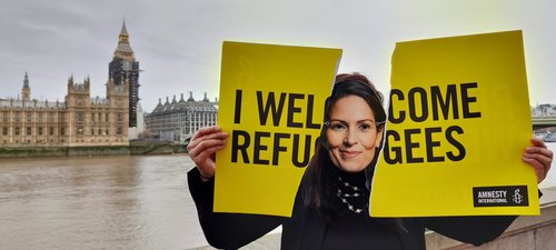 Priti Patel look-alike tears up a 'I Welcome Refugees’ sign