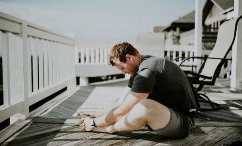 Person stretching whilst sitting on a deck