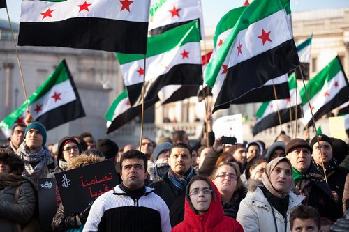 Women, men and children at a rally in London, UK carrying Syria flags
