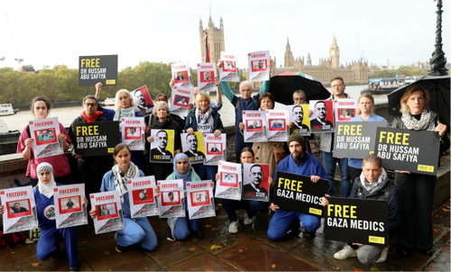 Medics wearing scrubs and activists holding placards reading “Free Gaza Medics”, “Free Dr Hussam Abu Safiya”, “Stop Arming Israel” the protesters stood against the backdrop of Parliament.