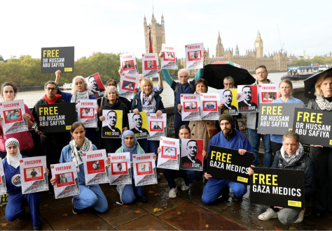 Medics wearing scrubs and activists holding placards reading “Free Gaza Medics”, “Free Dr Hussam Abu Safiya”, “Stop Arming Israel” the protesters stood against the backdrop of Parliament.