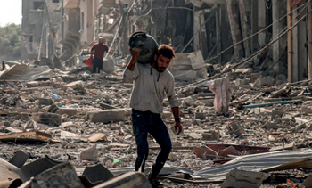 A man carries a propane gas cylinder in the Jabalia camp for Palestinian refugees in Gaza City on 11 October, 2023, amid destruction caused by Israeli air strikes