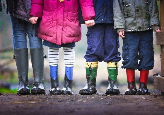 Four kids standing in a row in muddy wellies