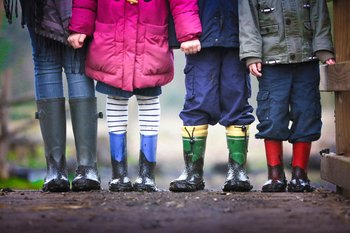 Four kids standing in a row in muddy wellies