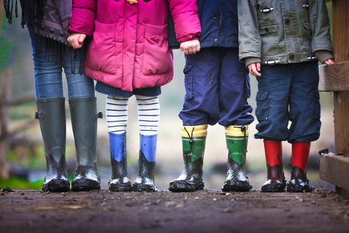 Four kids standing in a row in muddy wellies