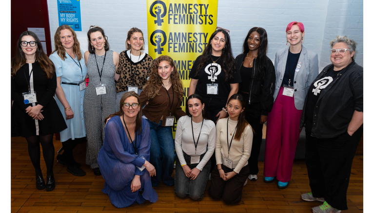 Whole team sitting infront of Feminist Network banners
