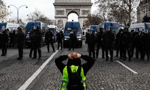 A protester kneeling in front of riot police in Paris, France.