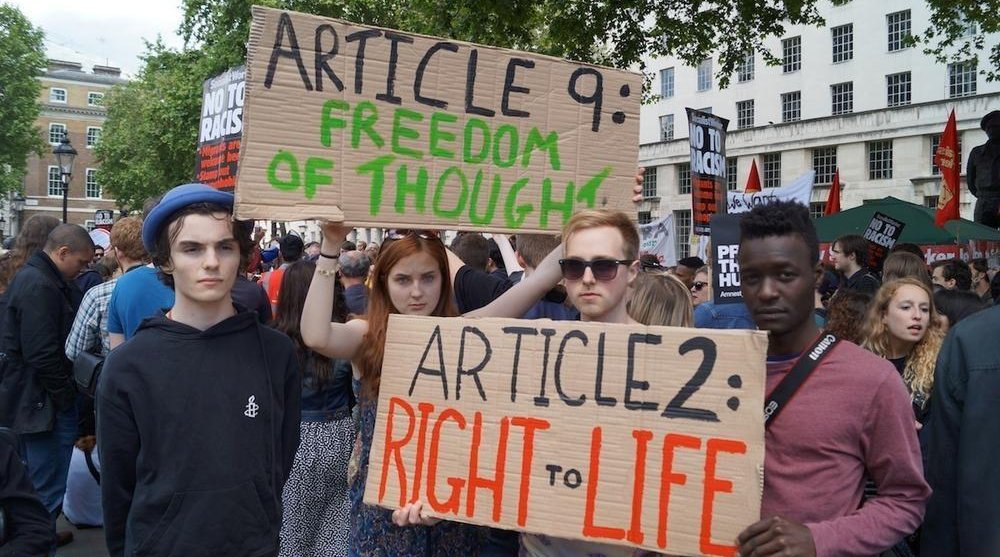 Protesters holding homemade placards that say 'Article: Freedom of Thought' and 'Article 2: Right to life'