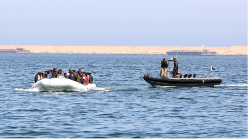 Libyan coast guards escort a boat carrying refugees and migrants