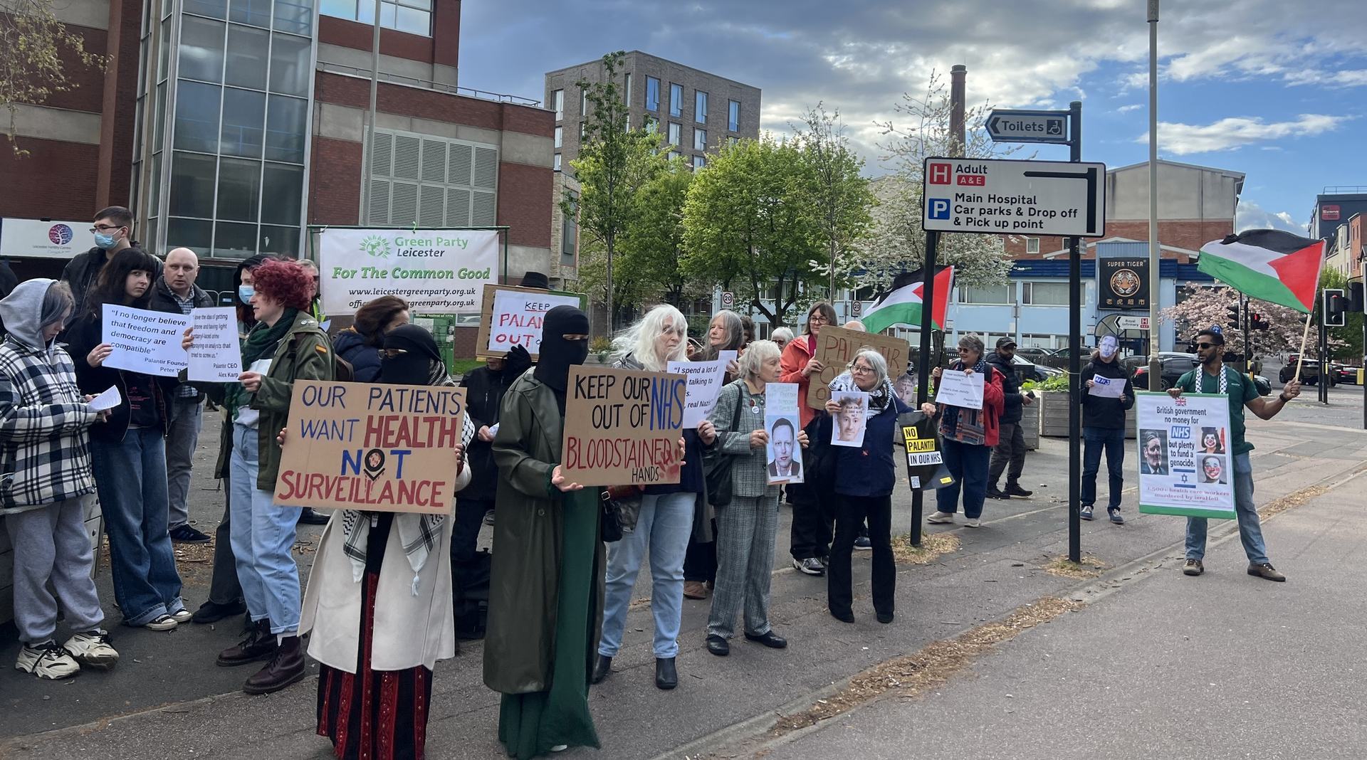 People standing outside holding placards opposing the company Palantir in our NHS