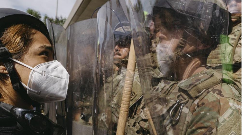 Protestor looking at National Guards holding riot shields