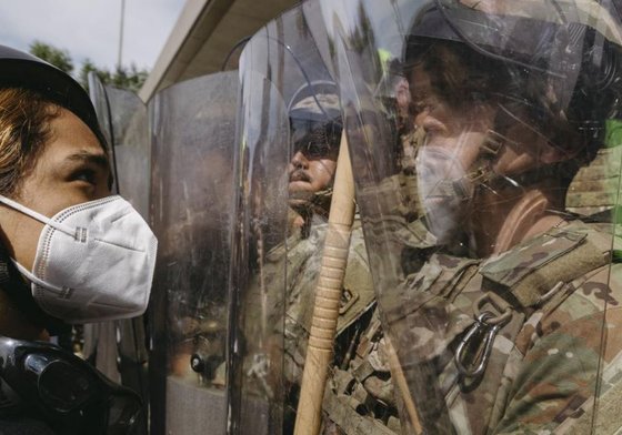 Protestor looking at National Guards holding riot shields