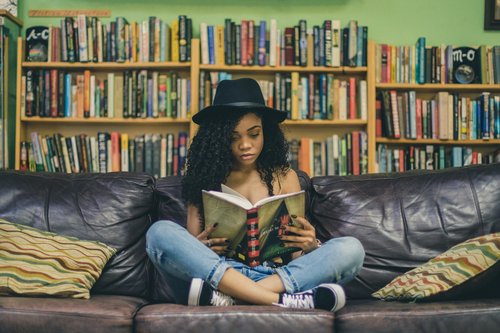 A woman sits cross-legged surrounded by books